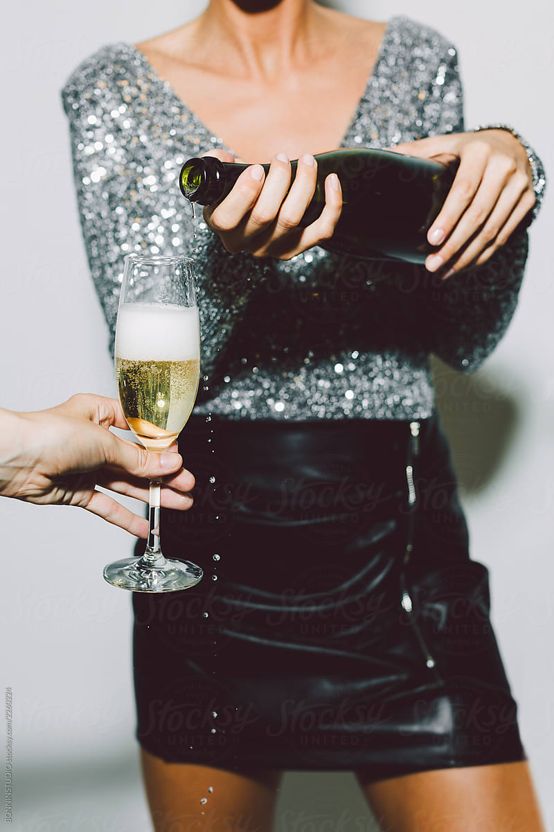 Anonymous woman serving a glass of champagne in a New Year party celebration.