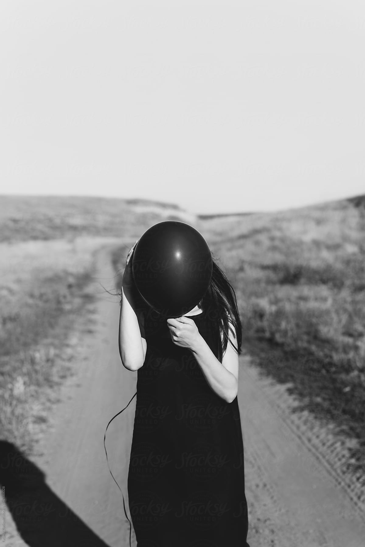 Woman in dark dress with black balloon