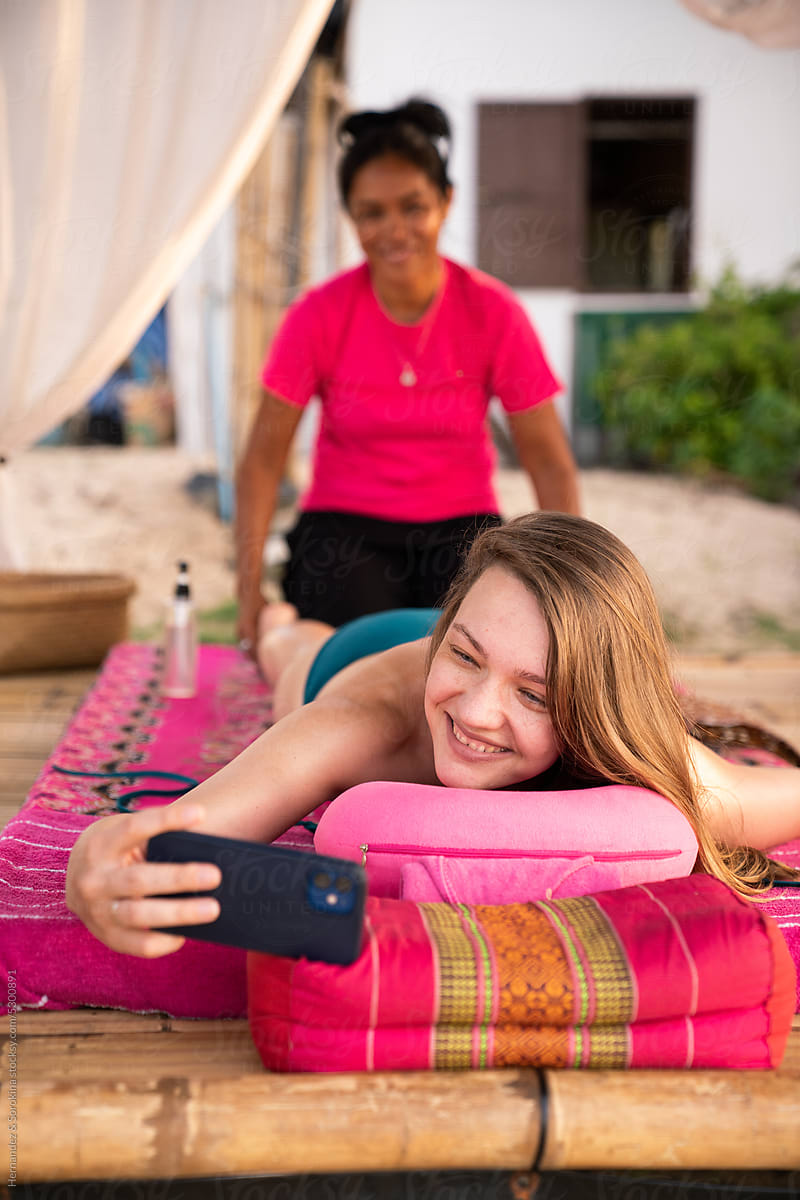 Happy Woman Using Phone While Receiving Massage