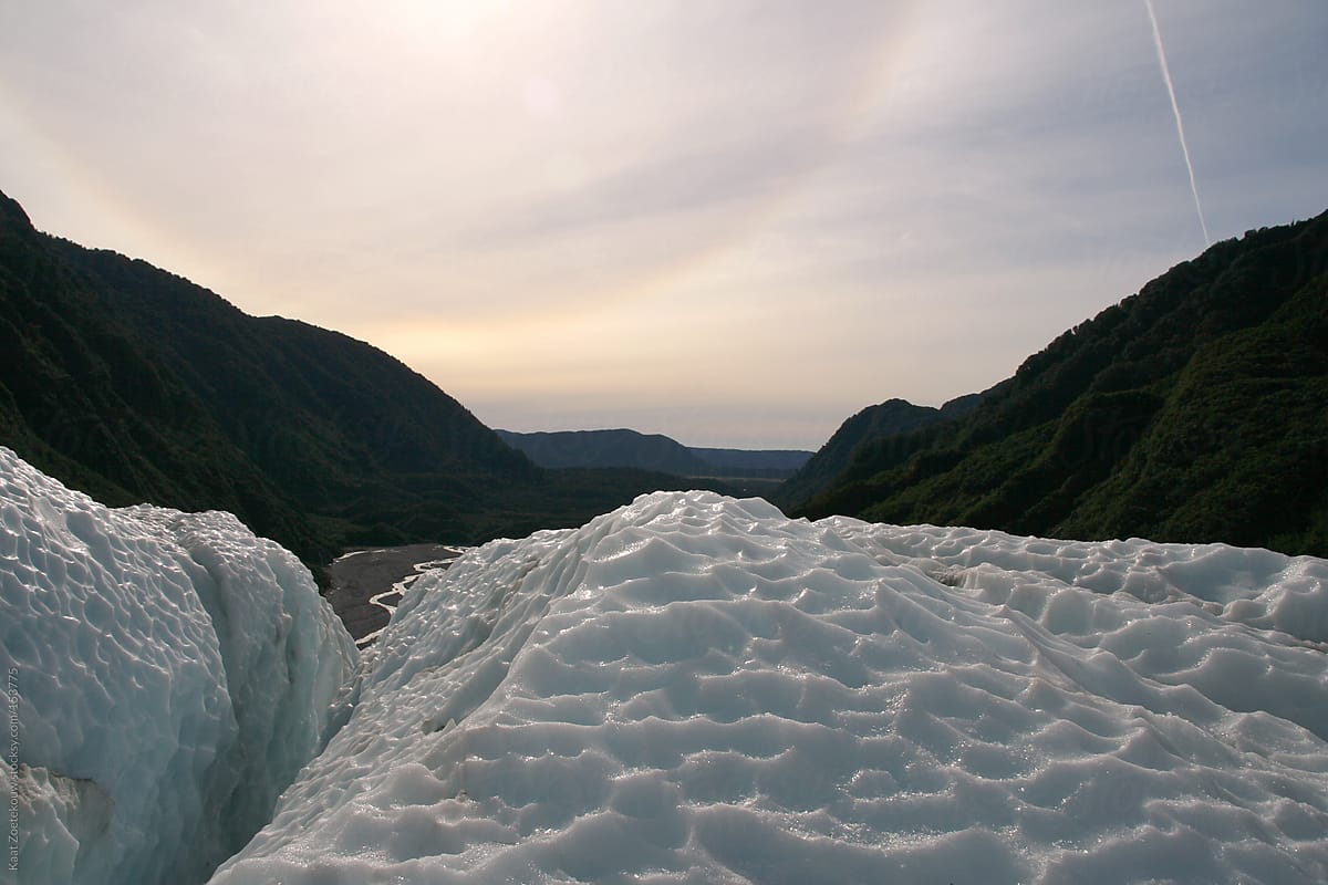 Icy landscape of the Franz Josef Glacier in New Zealand, lit by a halo-surrounded sun.