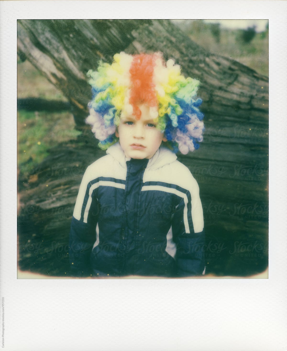 Four year old boy in jacket and rainbow clown wig isn\'t having it