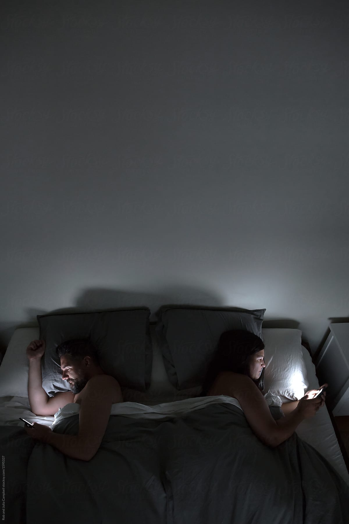 Couple Using Their Phones In Bed At Night By Stocksy Contributor Rob And Julia Campbell