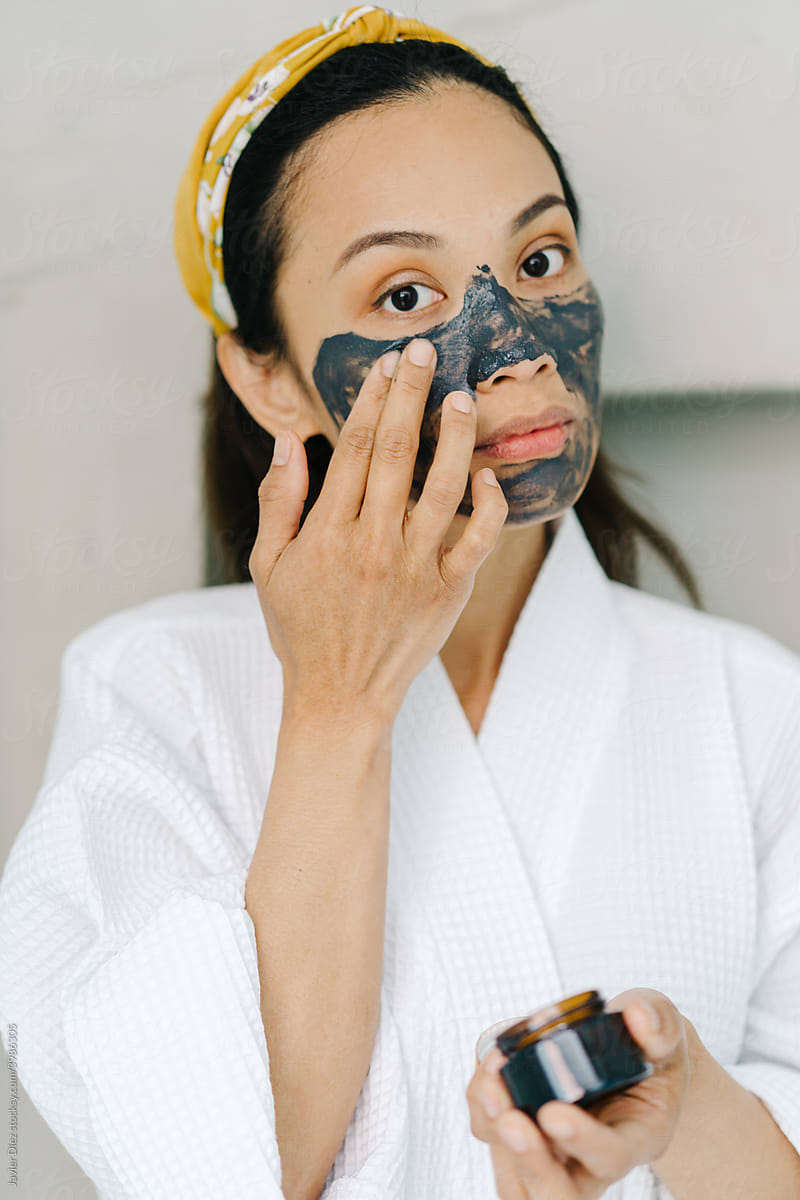 Asian female applying mask on face