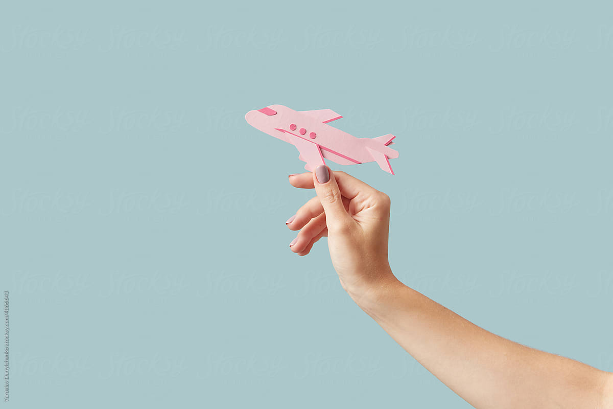 Pink paper craft airplane in woman\'s hand.
