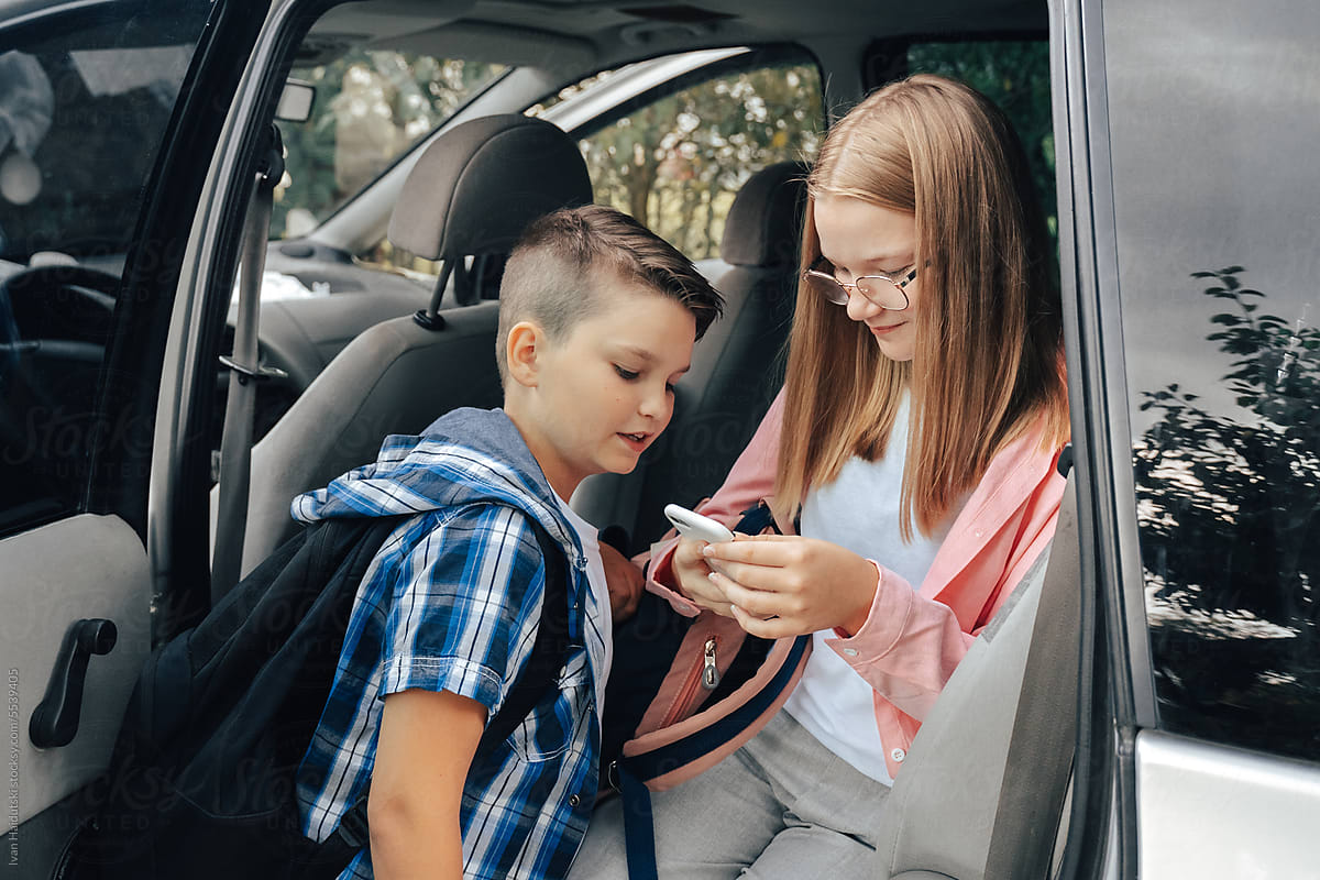 Teen Siblings Having Fun with Phones in Car After School
