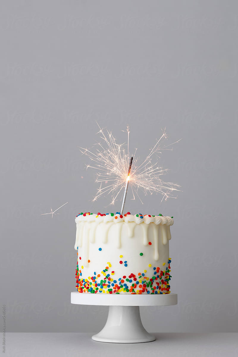 Birthday cake with white drip icing and colorful sugar sprinkles