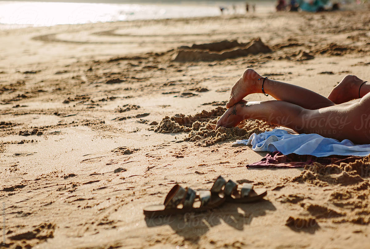 Two anonymous sunbathing womens legs on a beach