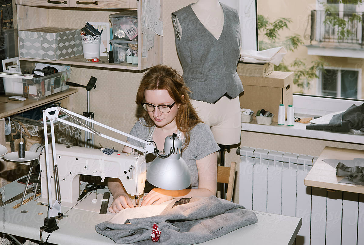 Young woman sewing at small atelier studio.