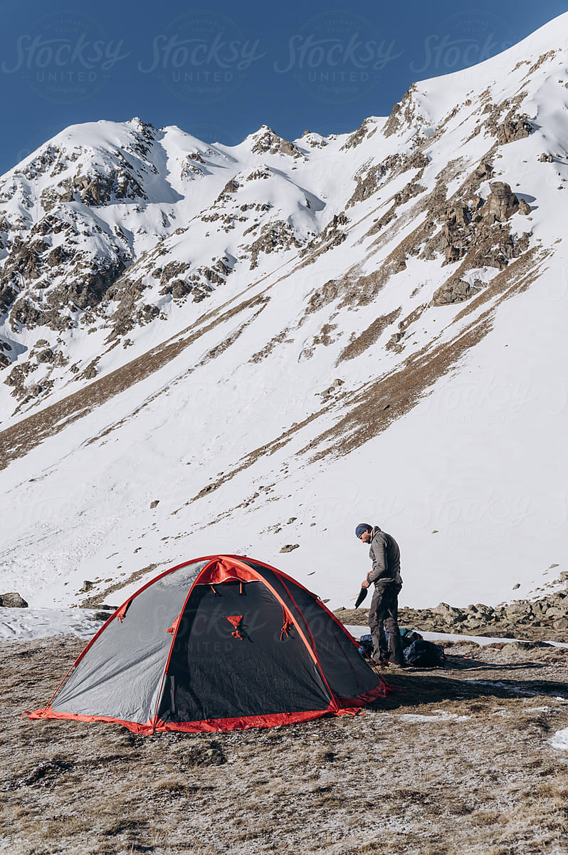 Traveler setting up tent near snowy mountain