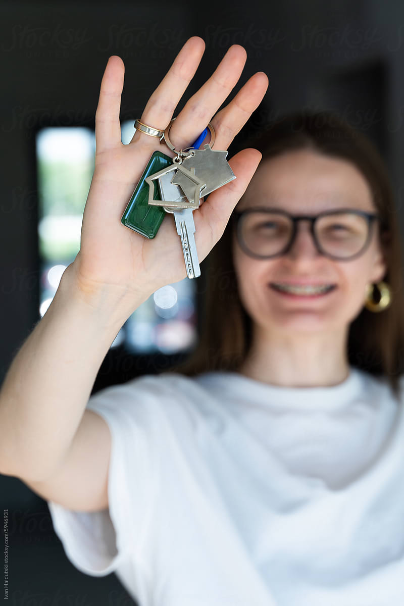 happy millennial woman holding key from a new home/apartment