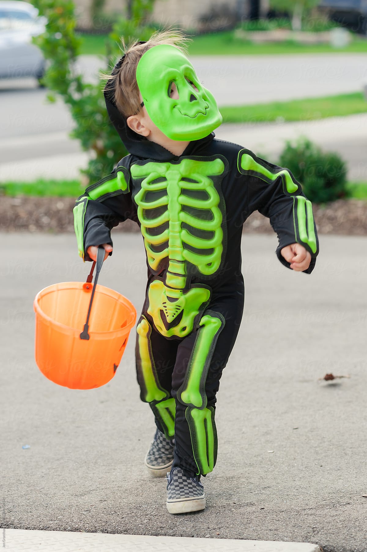 Toddler trick-or-treats in a skeleton costume