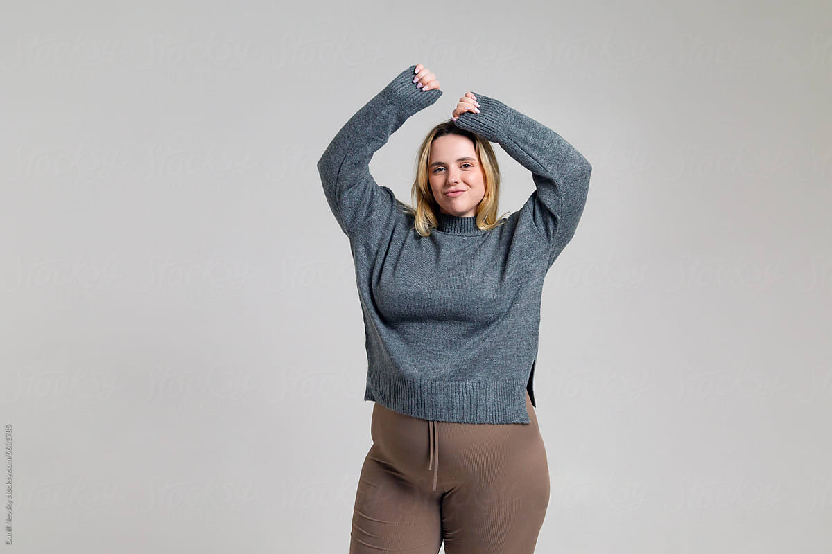 Happy young plus size woman standing with hands over head