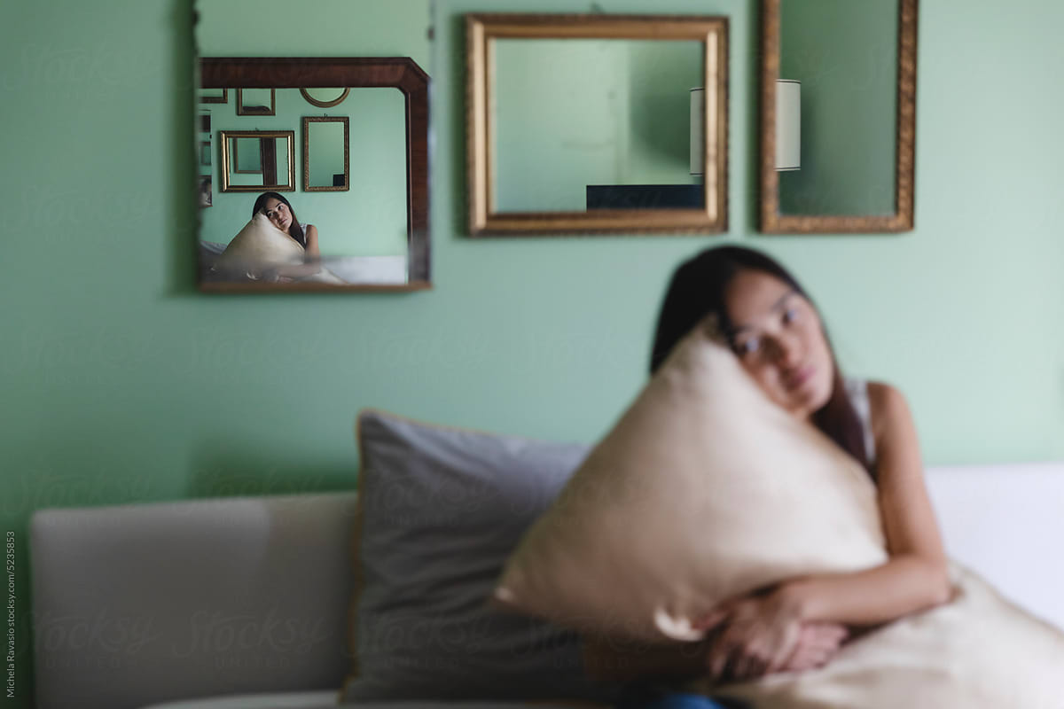Woman hugging pillow reflected in a mirror