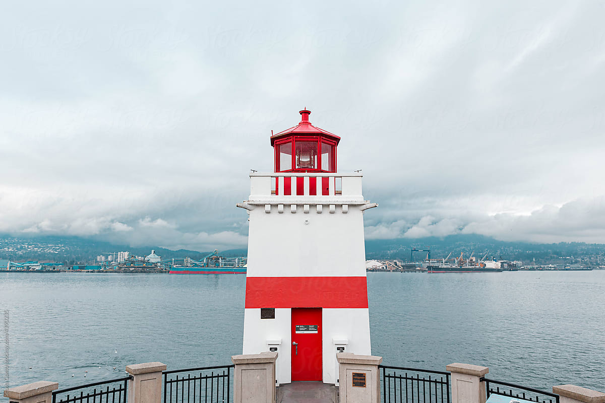 White lighthouse with red lines facing the sea