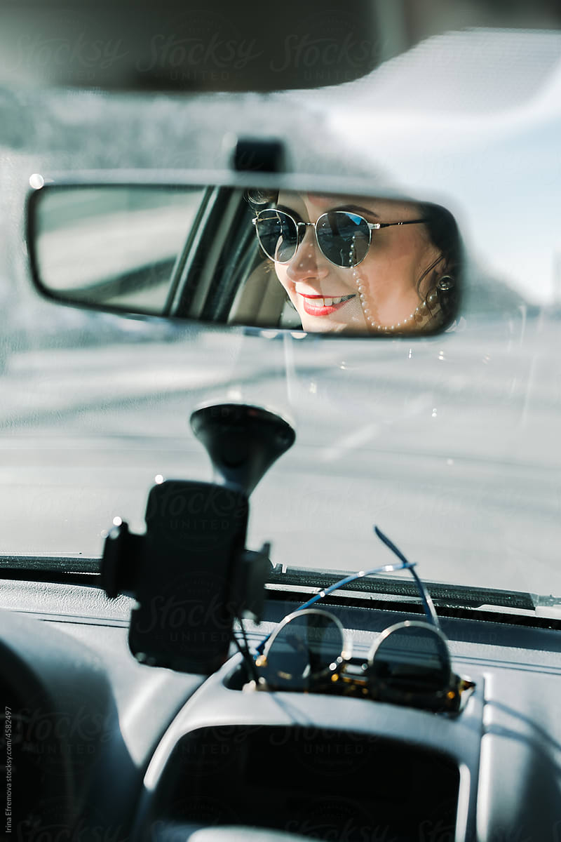 Woman smiling in a rear view car mirroor