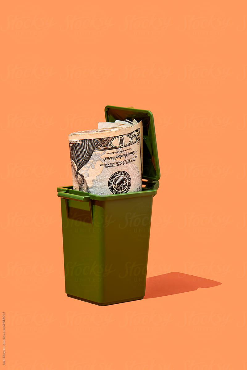 dollar banknotes in a trash can