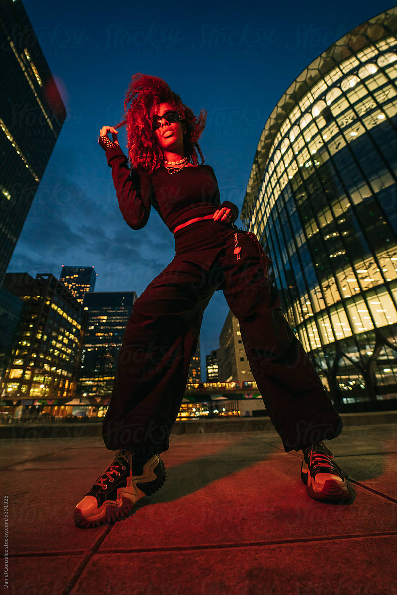 Black female in trendy outfit dancing on street in dusk