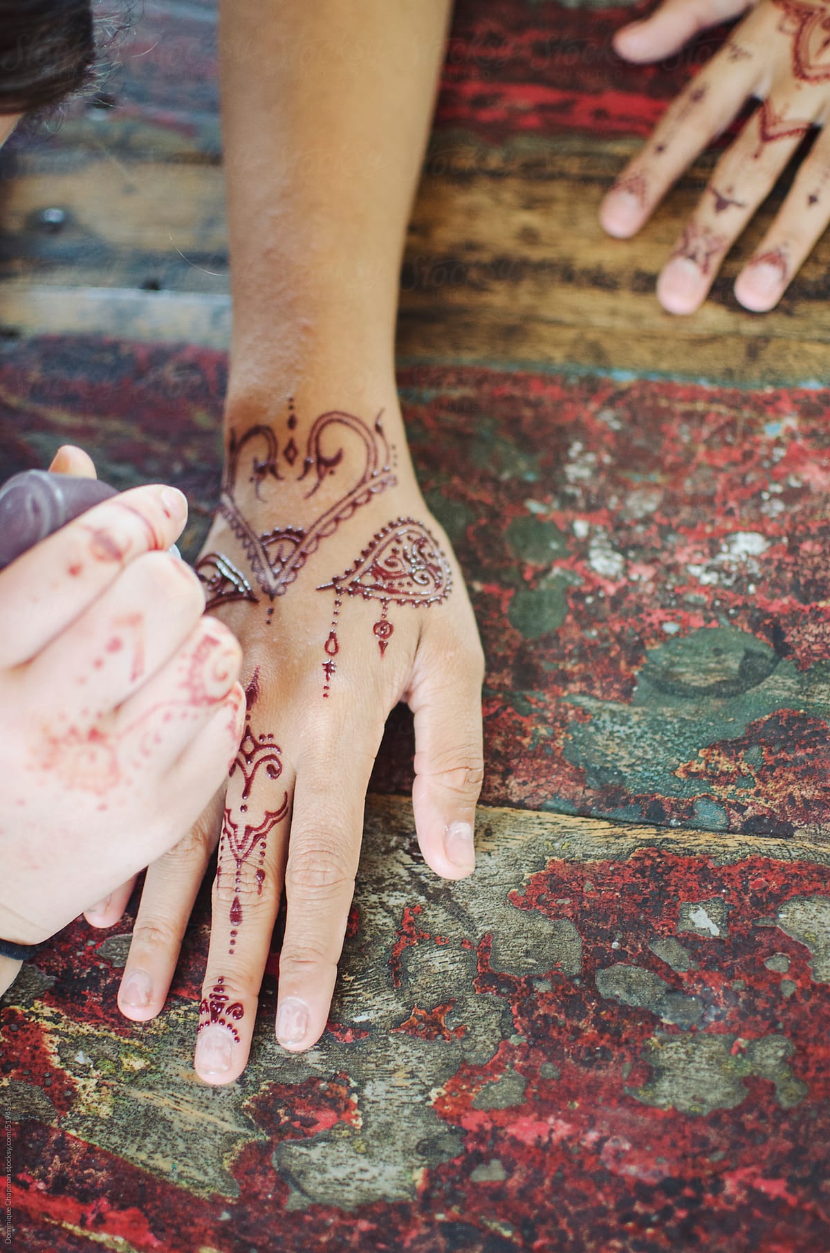 Henna tattoo being painted on hands