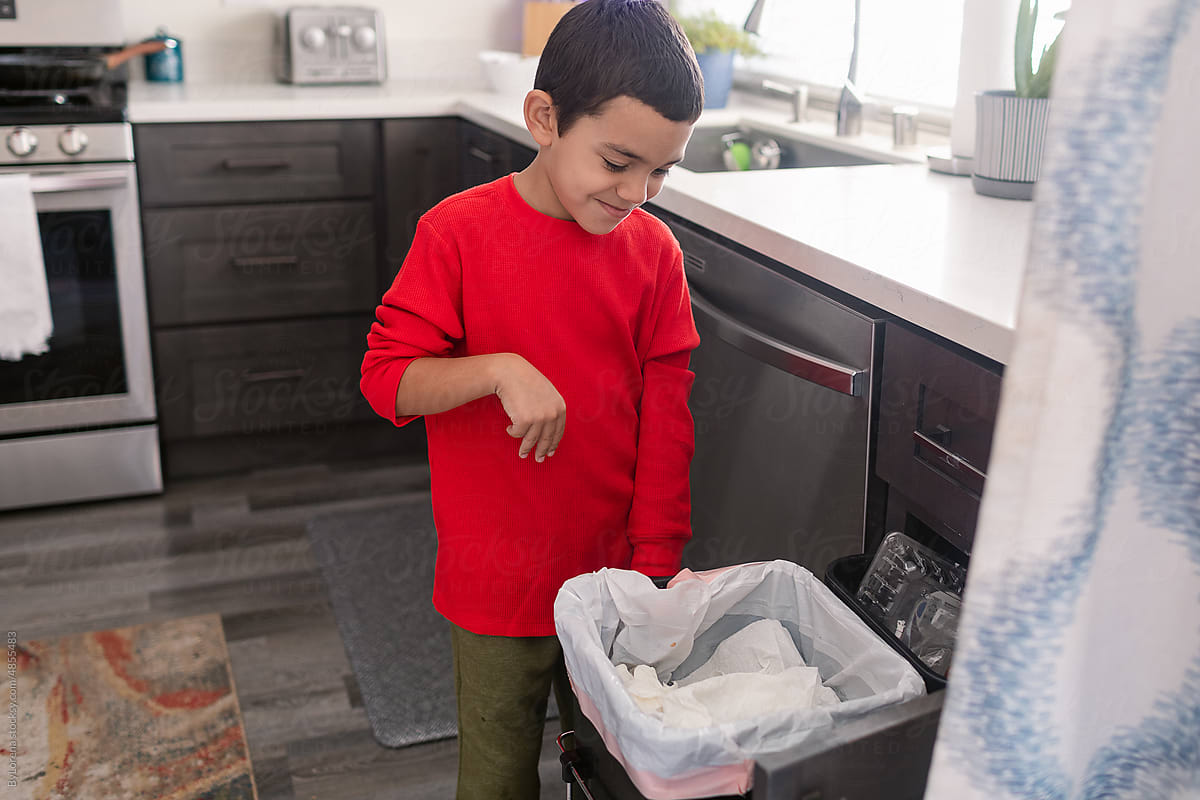 Young boy using recycling bins in kitchen
