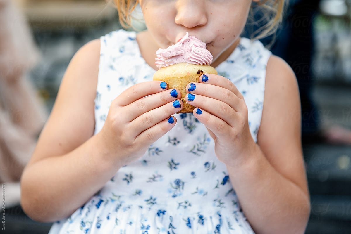 Little girl eats a cupcake at a party