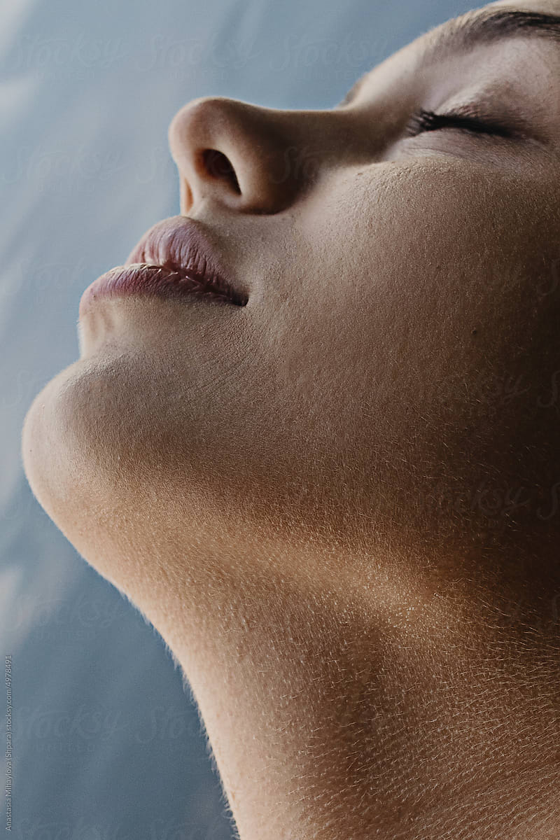 Half face profile portrait of a tanned woman with closed eyes in water