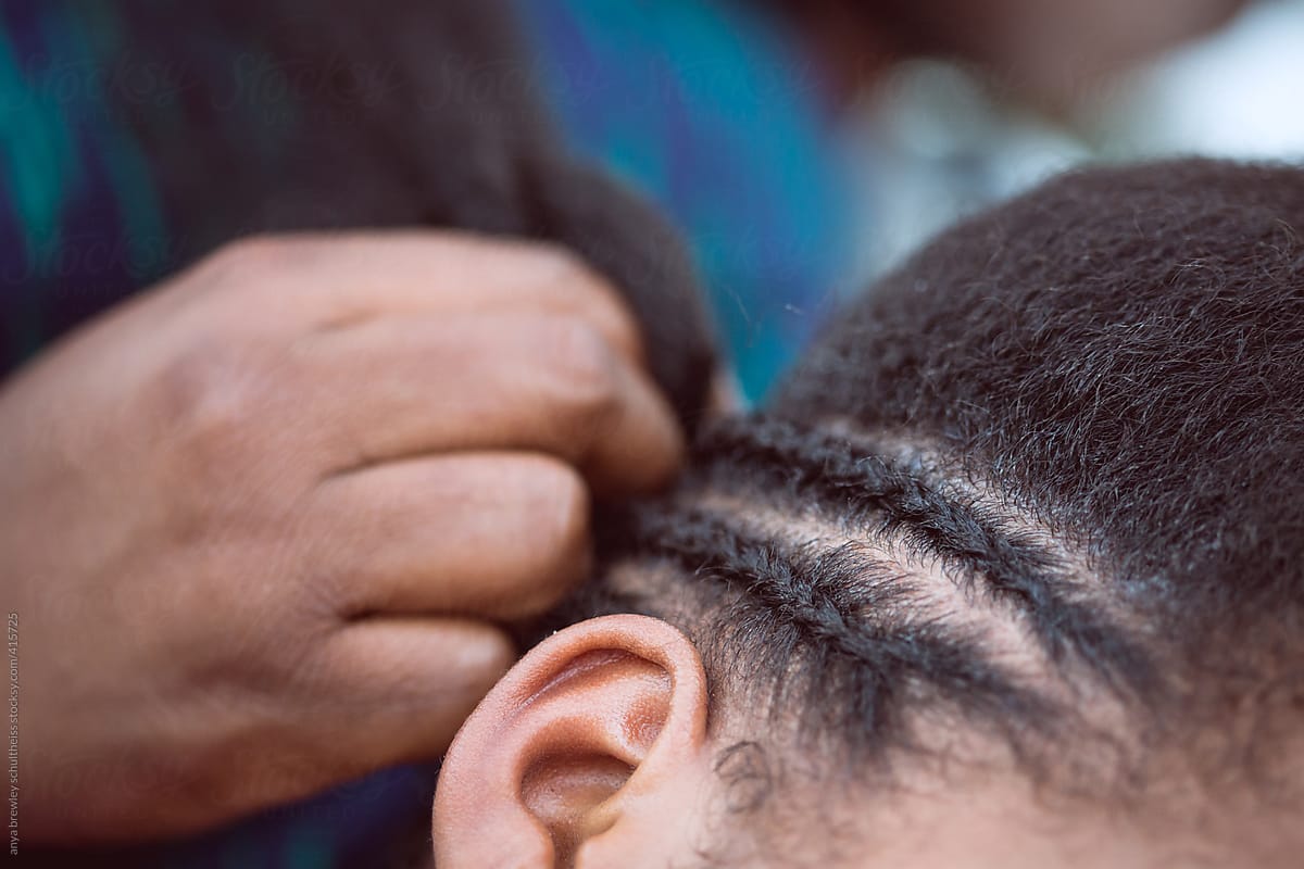 Young girl getting her curly kinky hair cornrowed