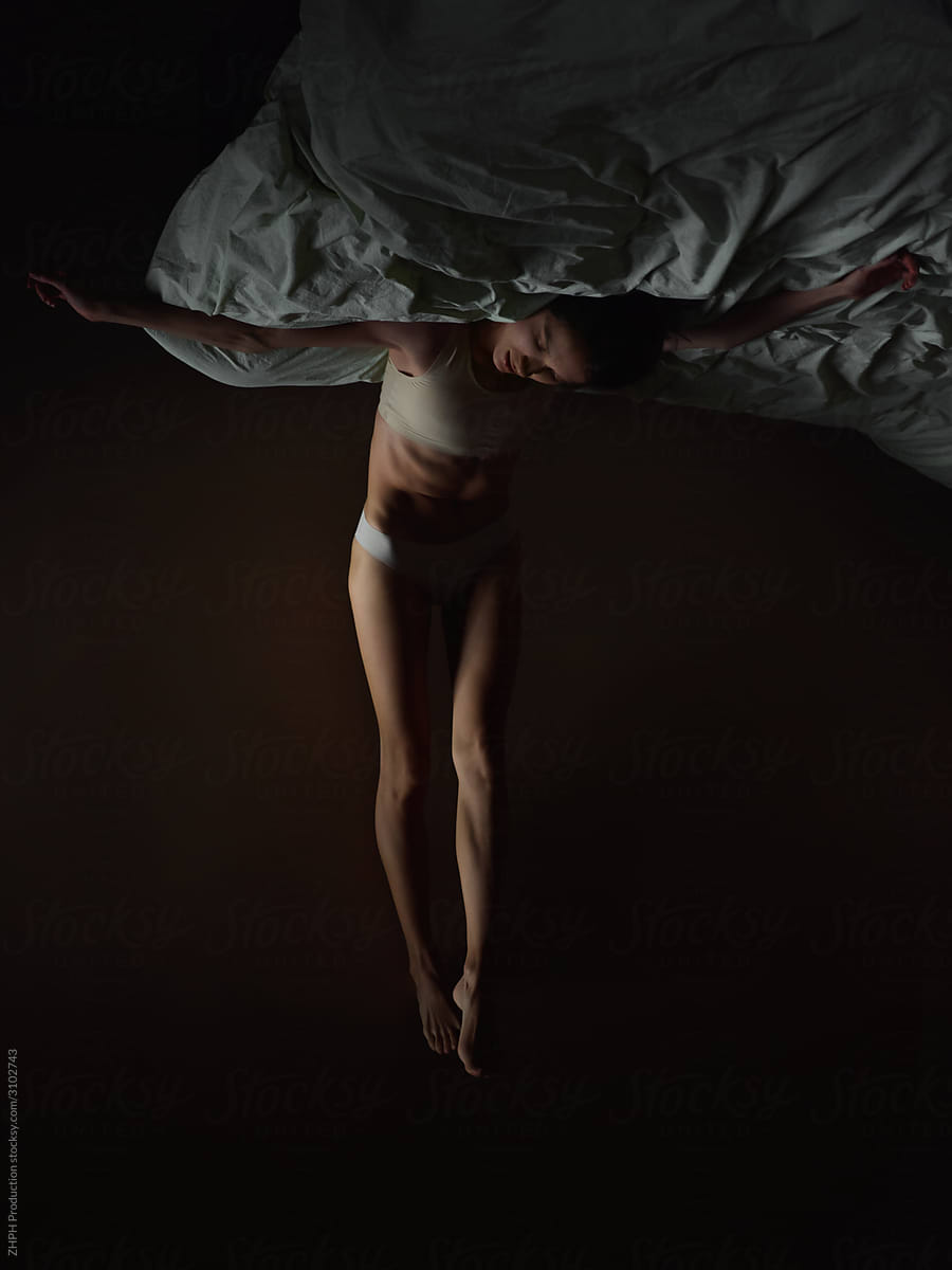 Woman crucifix posture on bed upside-down