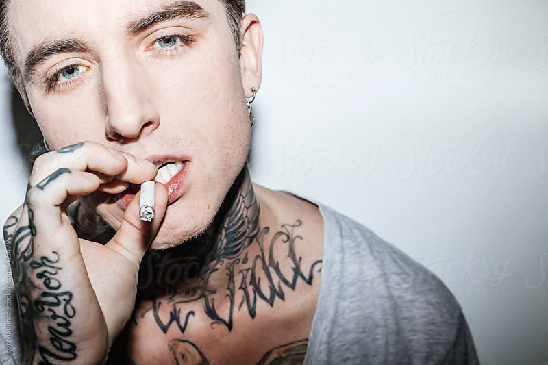 Fashionable tattooed guy with a modern haircut and a cigarette, attitude