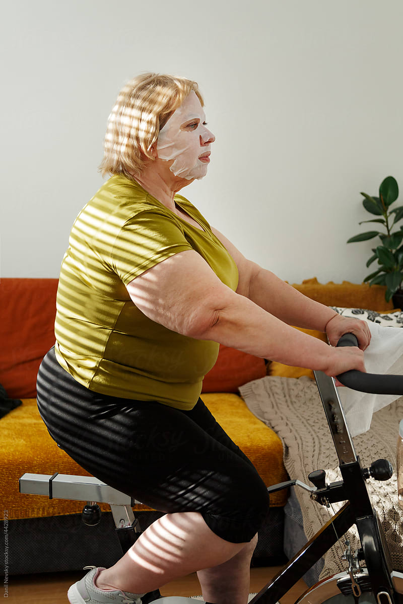 Mature woman with mask exercising at home