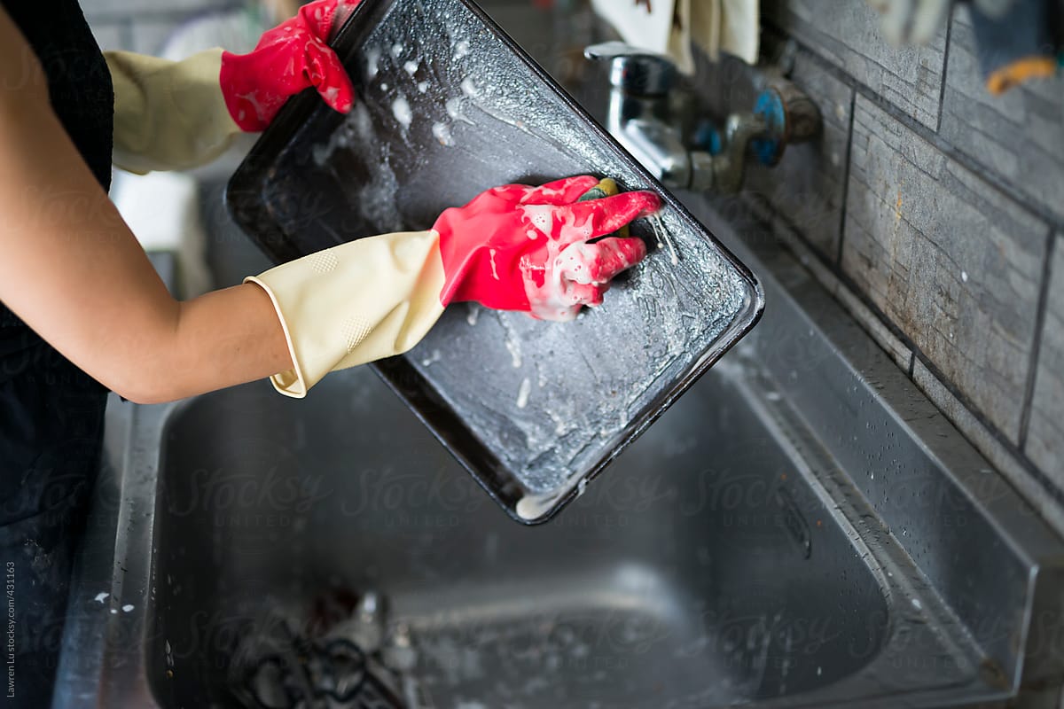 Hand with gloves doing dishwashing in sink