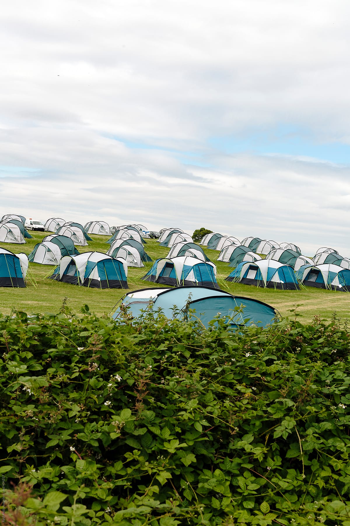 A large group of tents at a festival looking like bugs marching over a hill