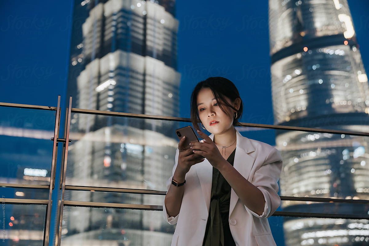 Asian woman using a phone before night city background