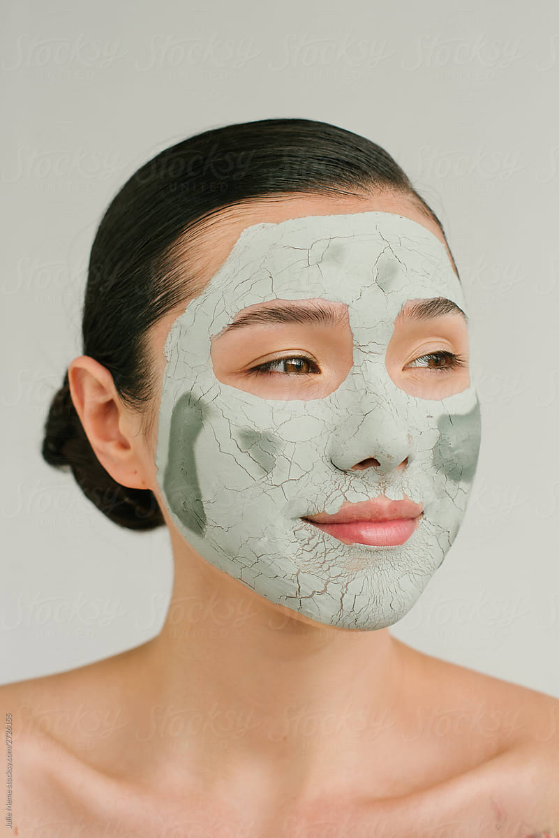 Closeup portrait of a charming Asian girl with a clay  mask on her face