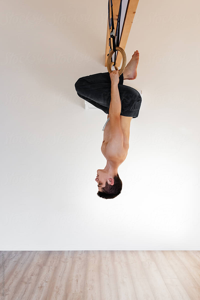 Young man doing acrobatic moves on rings