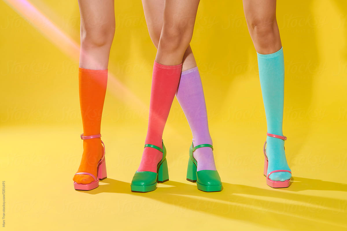 Female legs in colorful socks and shoes on yellow background