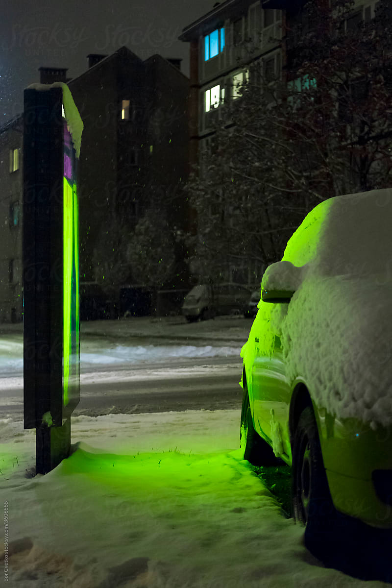 Green signboard and a green car in snow
