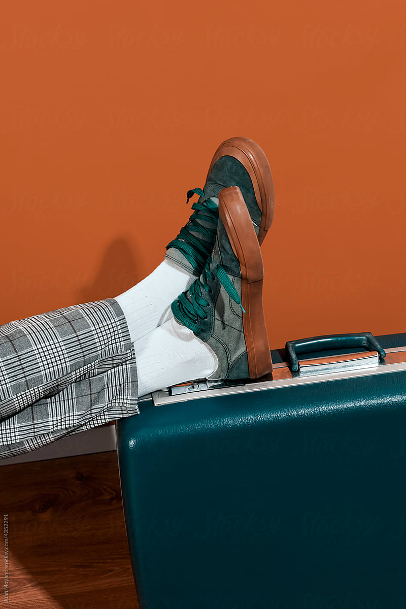 man leans his feet on a blue suitcase