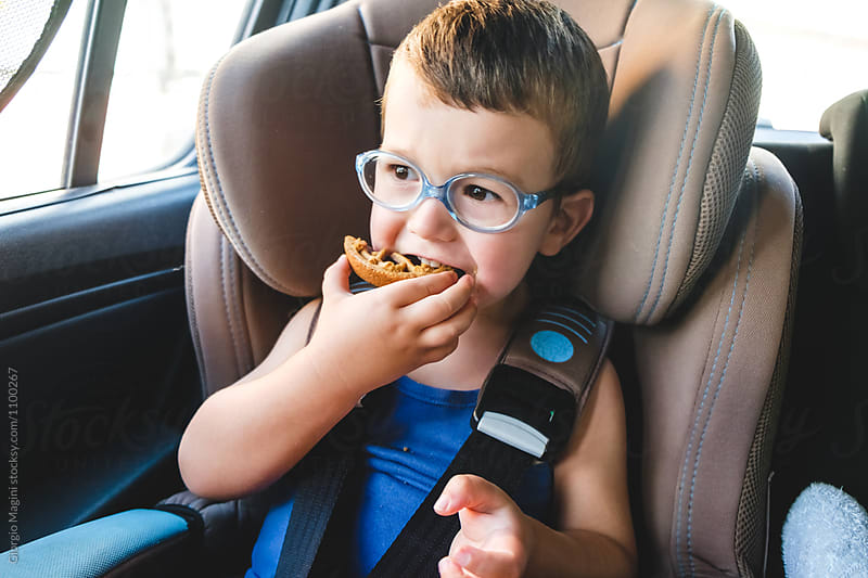 Toddler Boy Eating a Small Tart in a Baby Car Seat