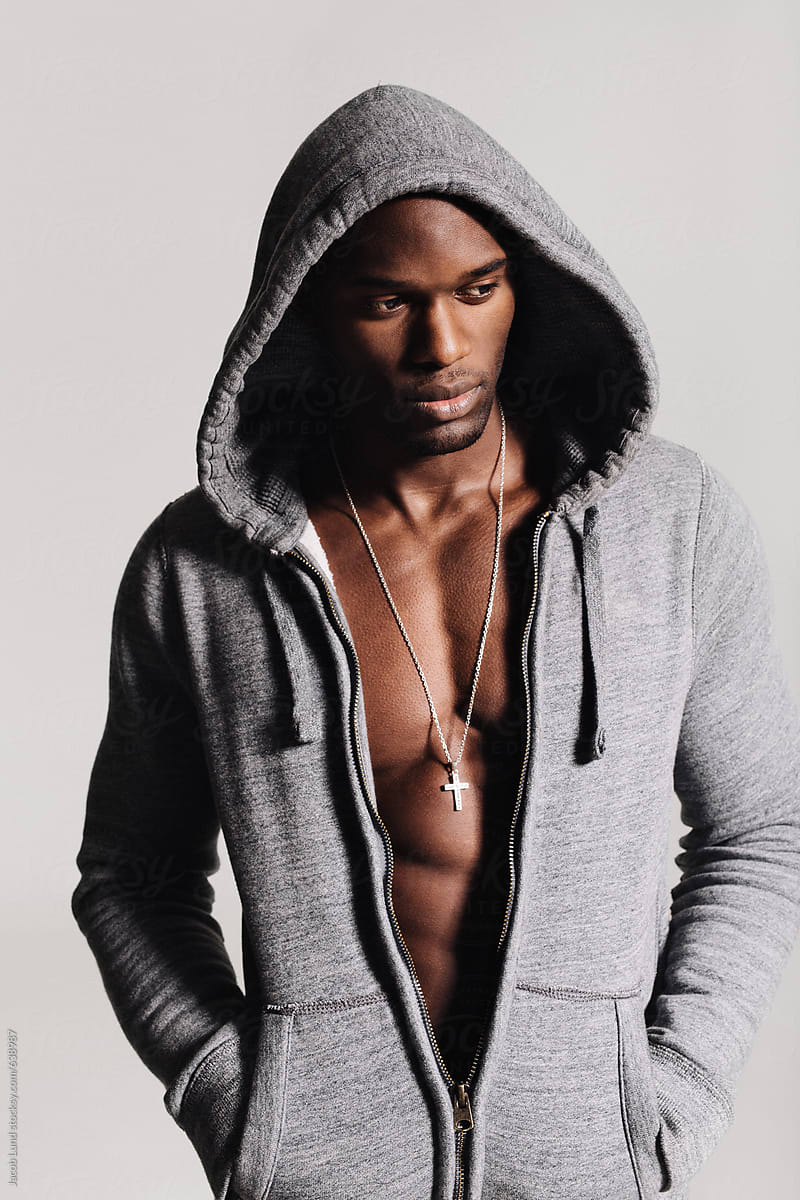 Handsome young man in hooded shirt with bare chest looking away