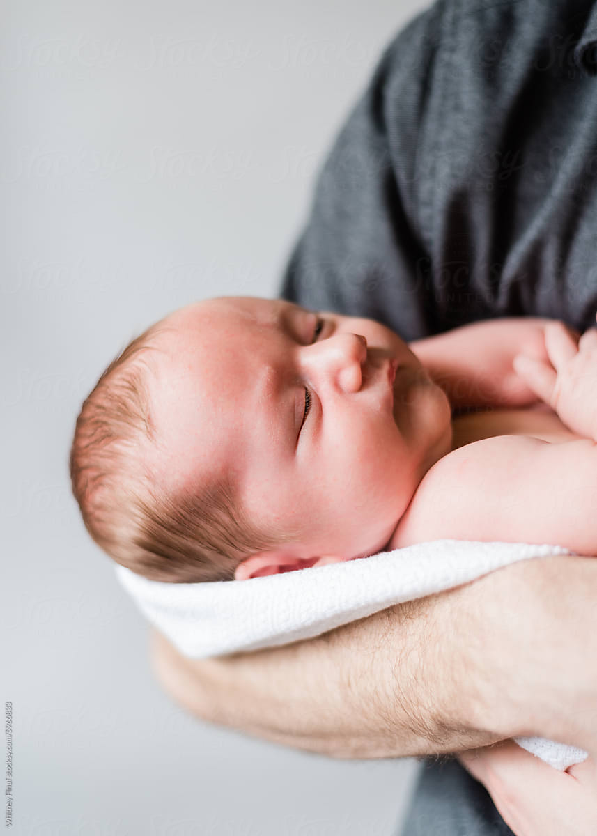 Newborn peacefully sleeps in father's safe arms