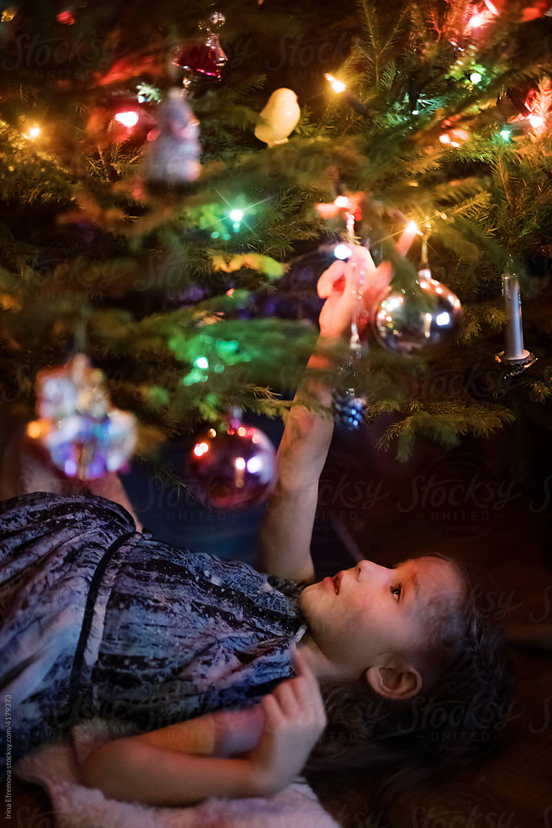 Little girl laying under a Christmas tree
