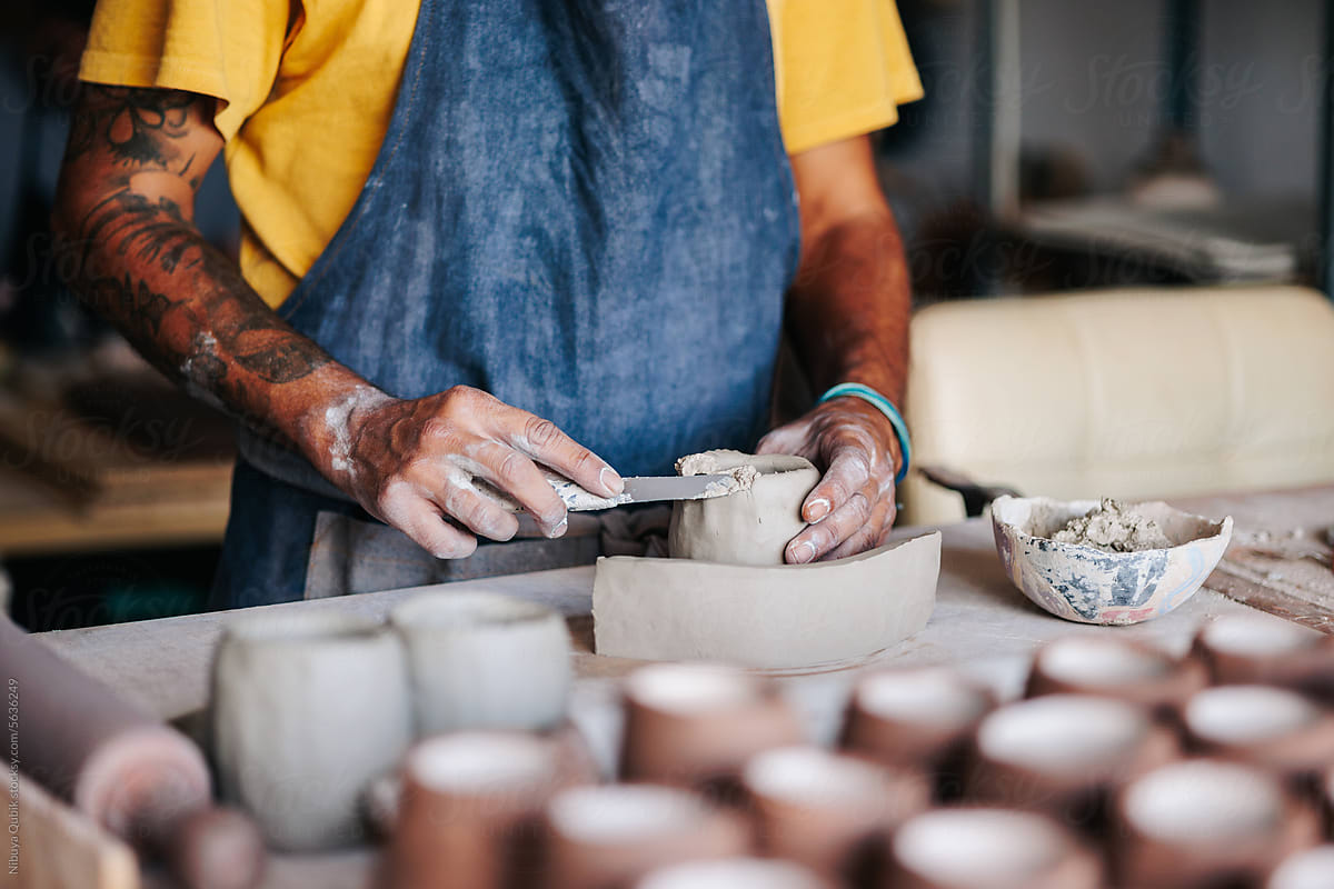 ceramist filling the rim of a freshly modelled vase with slips of clay