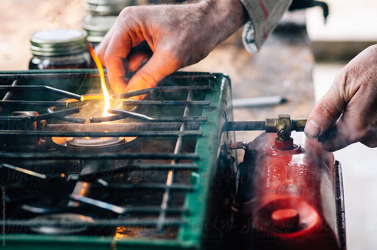 man ignites flame on camp stove