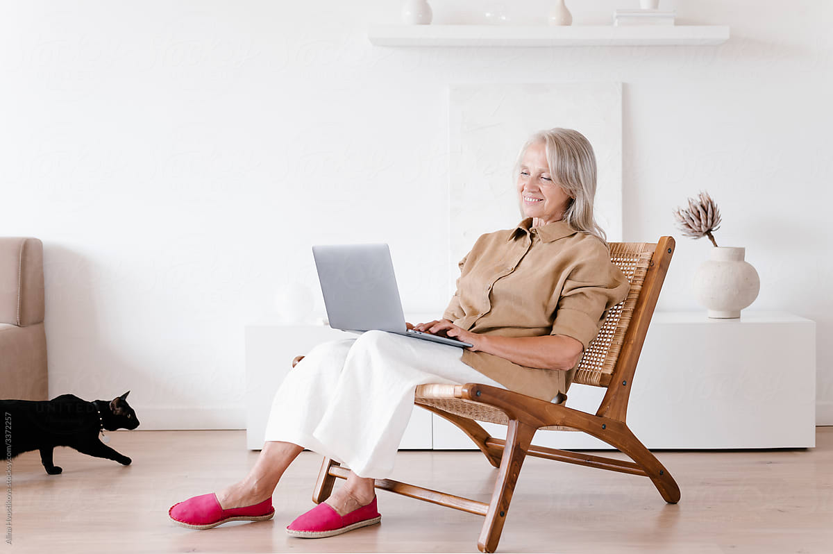 Happy senior woman using laptop on chair