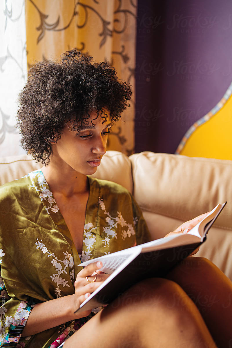black woman reading book at home