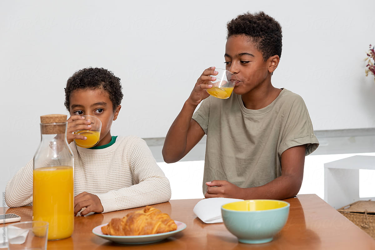 Two brothers drinking juice during breakfast