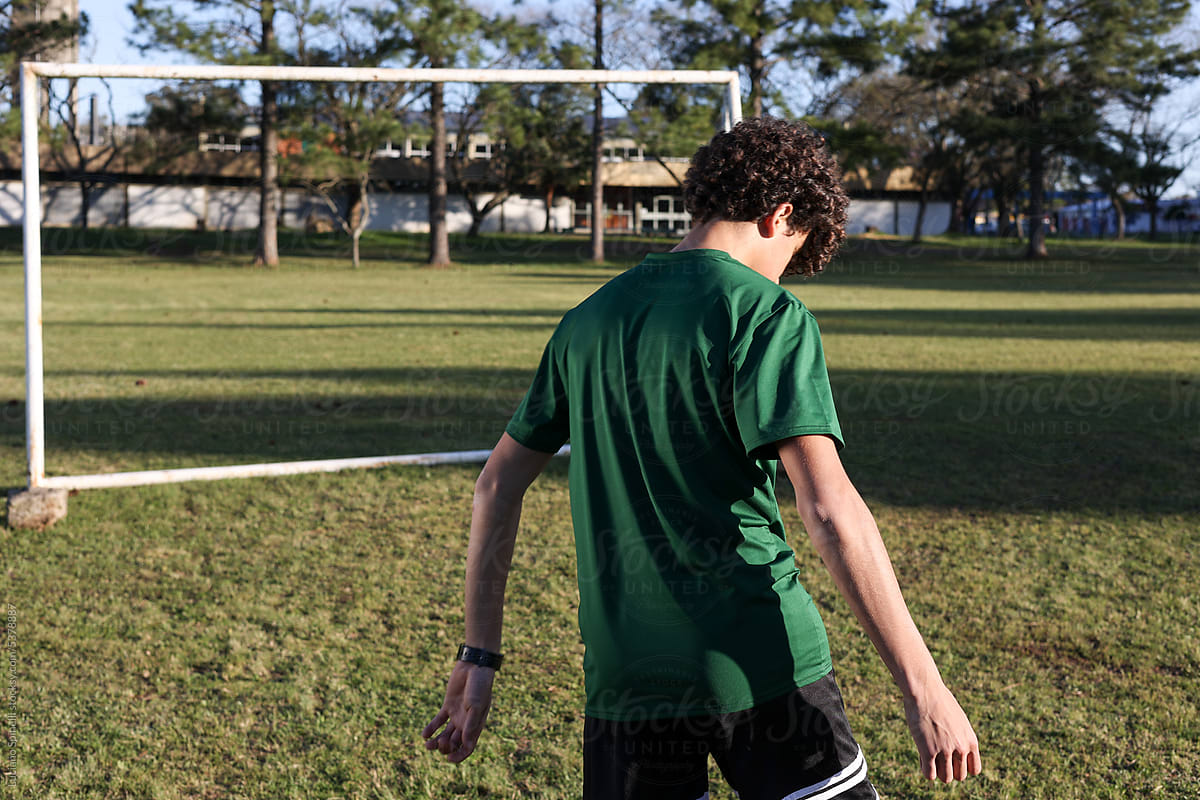 Sporty curly hair model seen from behind with arms open soccer field