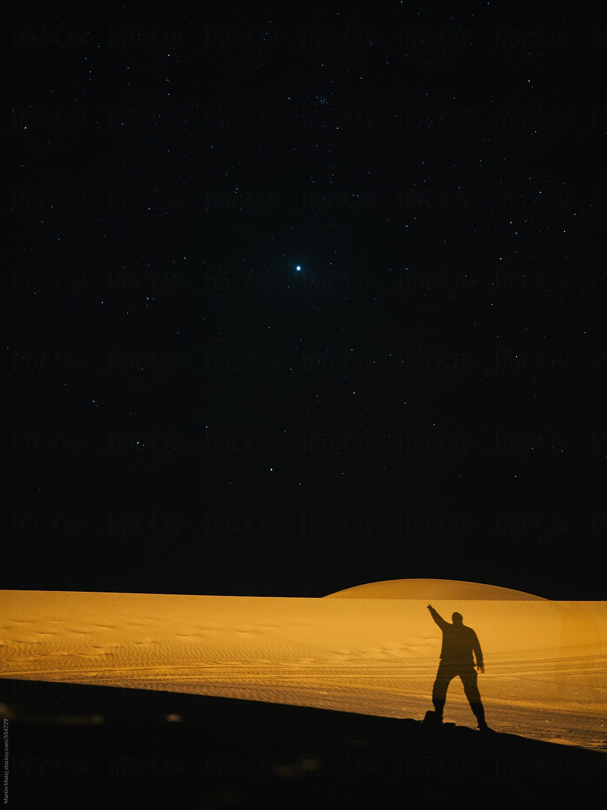 Silhouette in the desert pointing at the stars