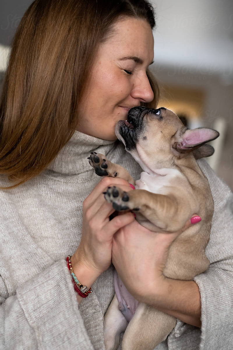 french bulldog puppy kissing a young woman
