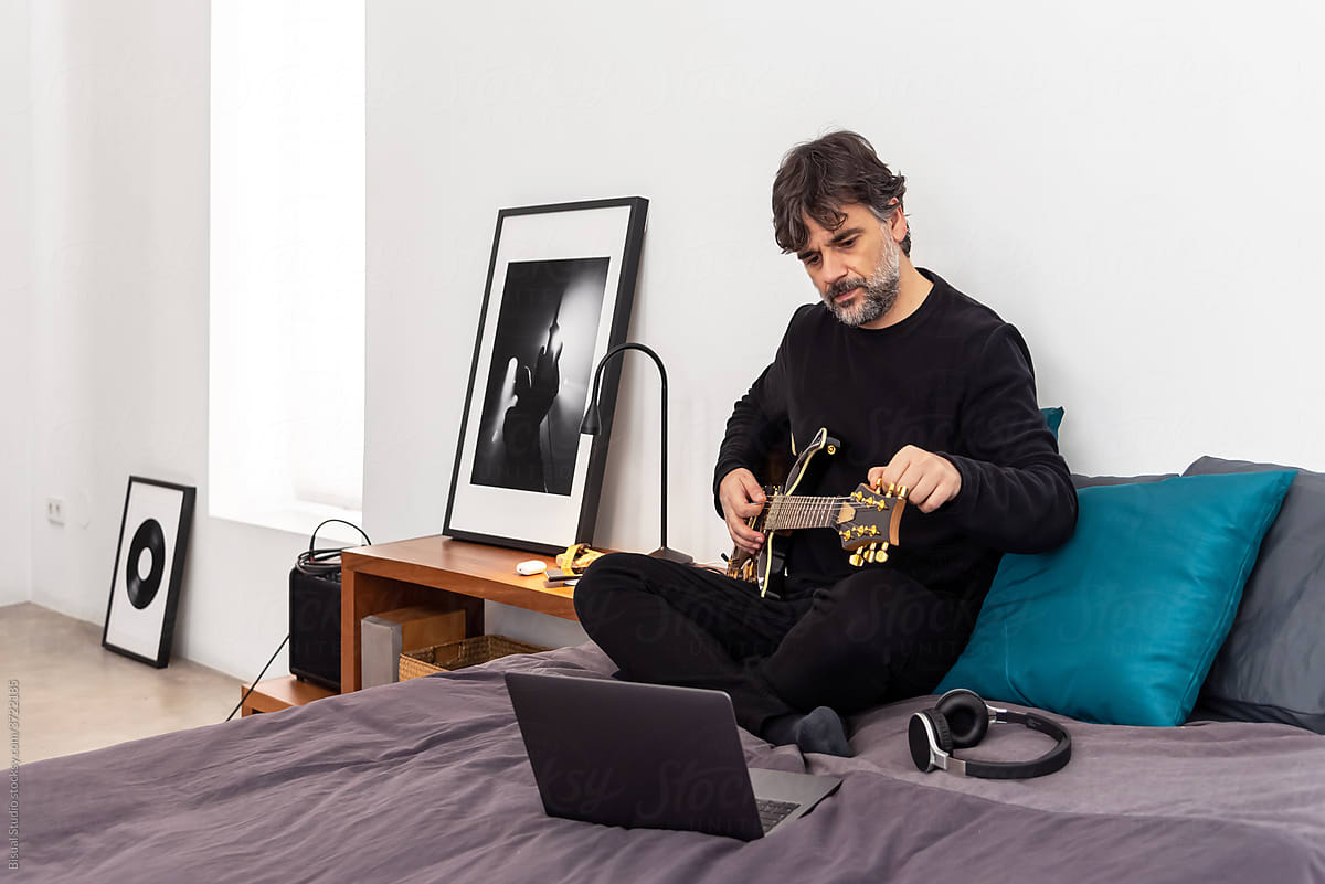 Man with laptop learning to play guitar